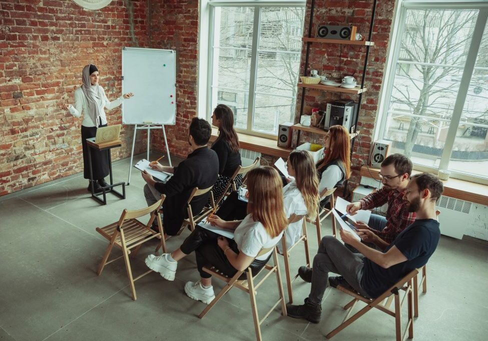 female-muslim-speaker-giving-presentation-hall-workshop-audience-hall-high-angle-view-participants-audience